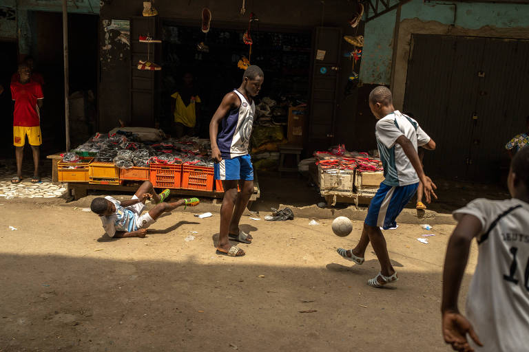 Jovens jogam futebol usamndo sandálias de plástico chamadas lêkê no mercado Adjamé em Abidjan, Costa do Marfim