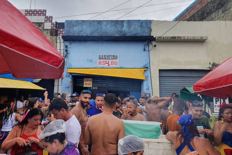 Foliões em frente a comércio que cobra R$ 4 para uso do banheiro durante a passagem do Galo da Madrugada