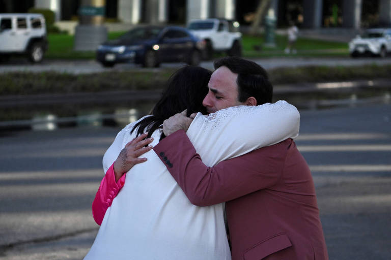 Pessoas que estavam presentes durante o ataque a tiros na megaigreja Lakewood se abraçam, em Houston