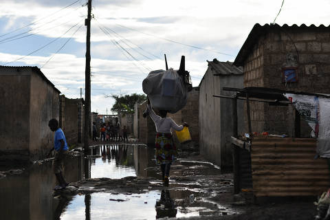 People walk across a flooded street in a neighbourhood affected by the cholera outbreak in Lusaka, Zambia January 18, 2024. REUTERS/Namukolo Siyumbwa ORG XMIT: GGG_NS03