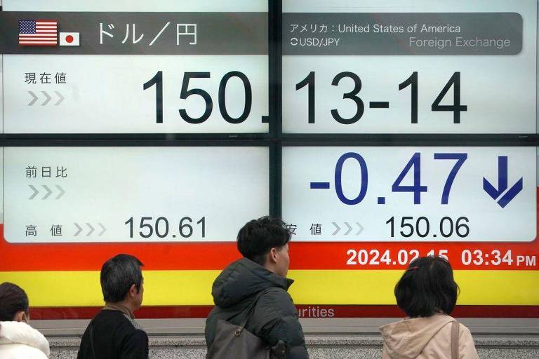 Japoneses passam em frente a uma tela que mostra a taxa de câmbio do iene em relação ao dólar