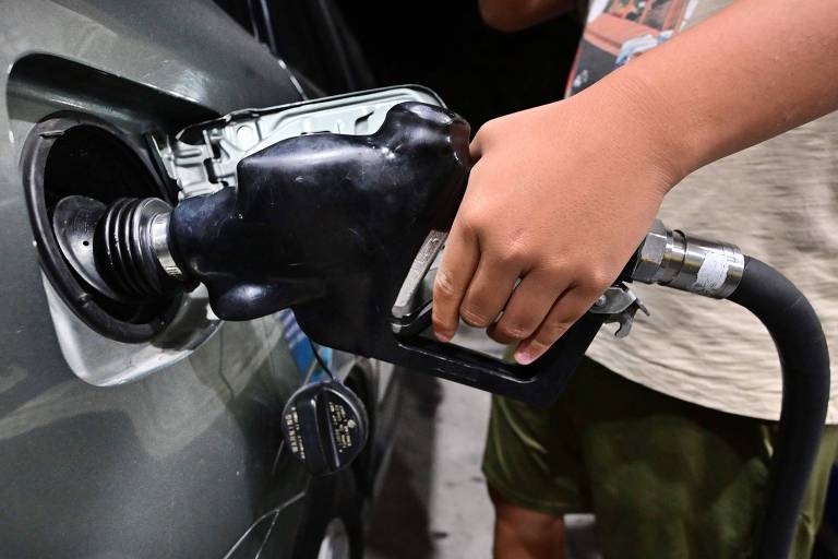 Homem coloca mangueira de combustível no tanque do carro para abastecimento em posto de gasolina nos Estados Unidos