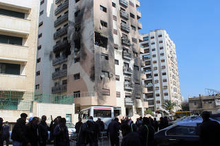 People gather near a damaged building in the Kafr Sousa district of Damascus