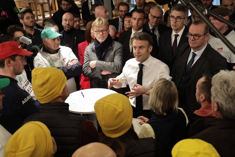 Cercado por sindicalistas, Emmnauel Macron (de camisa branca e gravata) conversa com agricultores em feira agrícola em Paris