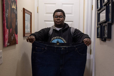 Billy Small III, who is under treatment with Novo Nordisk's weight-loss drug Wegovy, poses with a pair of trousers that he used to wear before starting with the drug treatment, at his home in Oakland, California, U.S., February 5, 2024. REUTERS/Carlos Barria   ONLY FOR USE WITH STORY HEALTH-OBESITY/ADOLESCENTS ORG XMIT: HFS-CB08