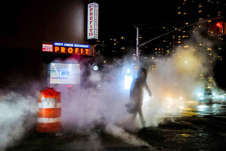 Em meio a uma área com vapor, mulher cruza uma rua durante um dia frio em Nova York 