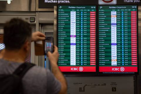 A man takes a picture of a screen displaying cancelled flights due to the national strike against the government of Javier Milei, at the Jorge Newbery airport in Buenos Aires, on January 24, 2024. Argentine President Javier Milei faces the first national strike in just 45 days of government, against his draconian fiscal adjustment and his plan to reform more than a thousand laws and regulations that governed for decades. The largest Argentine union called the strike in rejection, in particular, of the changes by decree to the labor regime promoted by Milei, which limit the right to strike and affect the financing of unions. (Photo by TOMAS CUESTA / AFP)