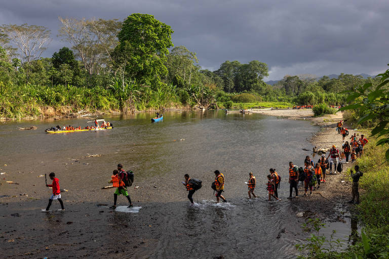 METETI， PANAMA. 31.01.2024: Migrantes atravessam o rio Tuqueza para chegar a área de embarque das canoas (piraguas) na comunidade indígena de Bajo Chiquito， que os levara ate a Estação de Recepção Migratória de Lajas Blancas. Bajo Chiquito é a primeira comunidade panamenha que os migrantes encontram após atravessarem a pé o estreito de Darién， uma área montanhosa de floresta densa entre a Colômbia e o Panamá. (Foto: Lalo de Almeida/Folhapress)