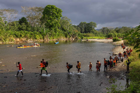 METETI, PANAMA. 31/01/2024. ESPECIAL DARIEN. Migrantes atravessam o rio Tuqueza para chegar a area de embarque das canoas ( piraguas ) na comunidade indígena de Bajo Chiquito, que os levara ate a Estacao de Recepcao Migratoria de Lajas Blancas. Bajo Chiquito e a primeira comunidade panamenha que os migrantes encontram apos atravessarem a pe o estreito de Darien, uma area montanhosa de floresta densa entre a Colombia e o Panama. ( Foto: Lalo de Almeida/Folhapress ). MUNDO. *** EXCLUSIVO FOLHA***