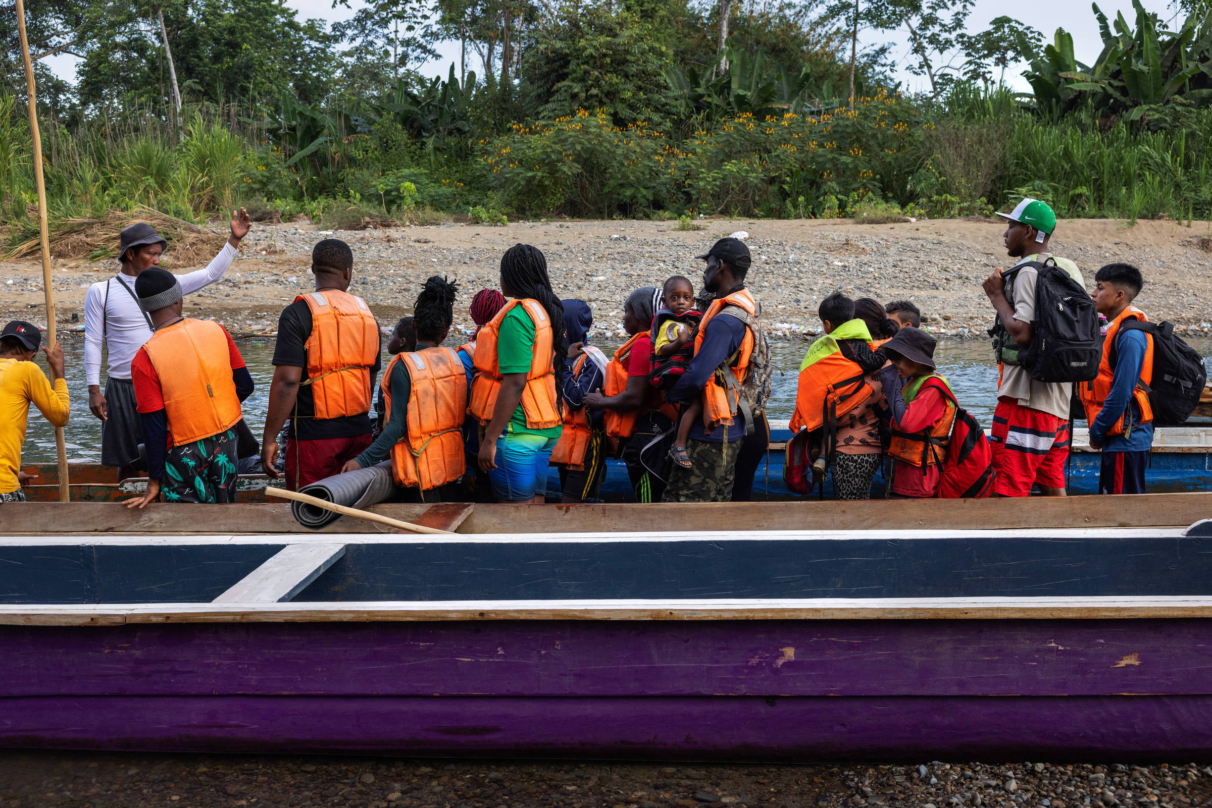 O brasileiro Fiedimio, 3, no colo do pai; eles se preparam para embarcar em uma canoa na comunidade indígena de Bajo Chiquito que os levará pelo rio Tuqueza até uma estação migratória