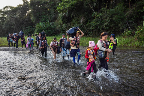 METETI, PANAMA. 31/01/2024. ESPECIAL DARIEN. Migrantes atravessam o rio Tuqueza para chegar a area de embarque das canoas ( piraguas ) na comunidade indígena de Bajo Chiquito, que os levara ate a Estacao de Recepcao Migratoria de Lajas Blancas. Bajo Chiquito e a primeira comunidade panamenha que os migrantes encontram apos atravessarem a pe o estreito de Darien, uma area montanhosa de floresta densa entre a Colombia e o Panama. ( Foto: Lalo de Almeida/Folhapress ). MUNDO. *** EXCLUSIVO FOLHA***