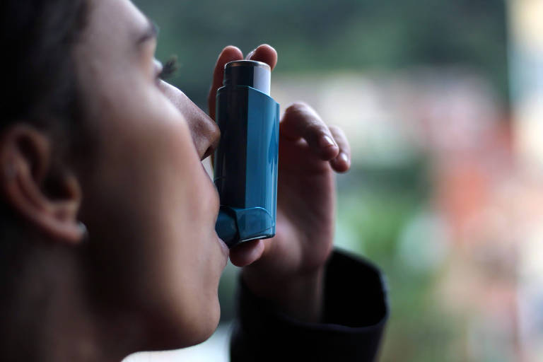 Jovem usando inalador de asma azul para prevenir um ataque de asma. Produto farmacêutico para prevenir e tratar a asma.