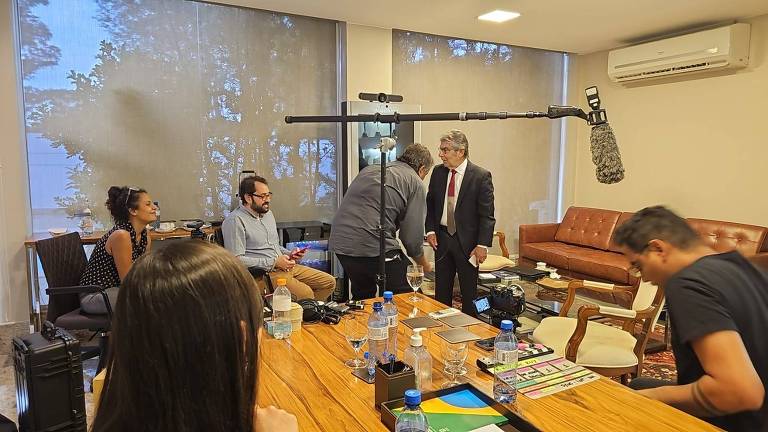 ex-ministro Ayres Britto de terno e gravata em seu gabinete com equipamentos de filmagem e de captação de som e funcionários da produção de documentário