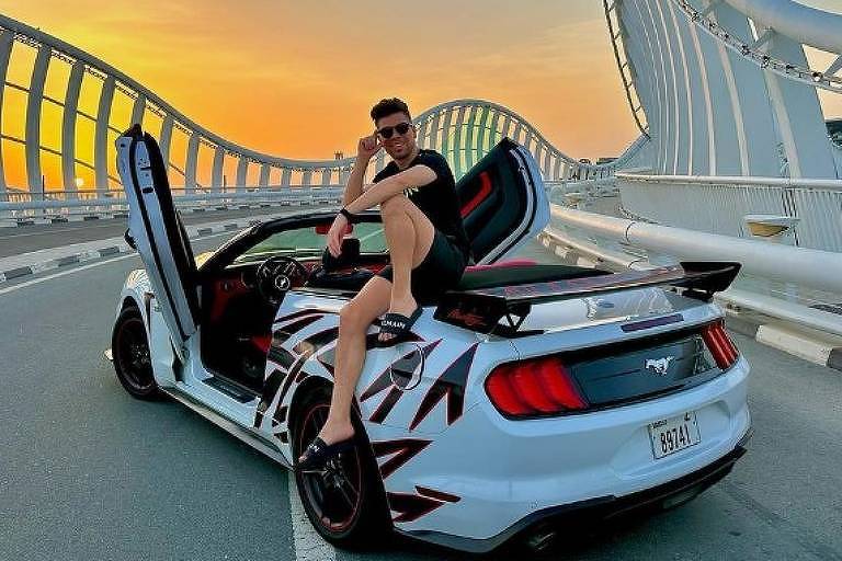 O empresário Alan Deivid de Barros, preso pela Polícia Federal suspeito de envolvimento em fraudes com criptomoedas, sentado sobre um carro de luxo em Dubai, nos Emirados Árabes Unidos