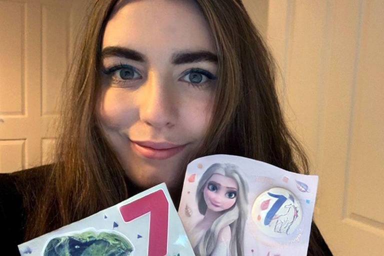 Júlia mostra seus cartões com o número 7 em seu sétimo aniversário em ano bissexto
