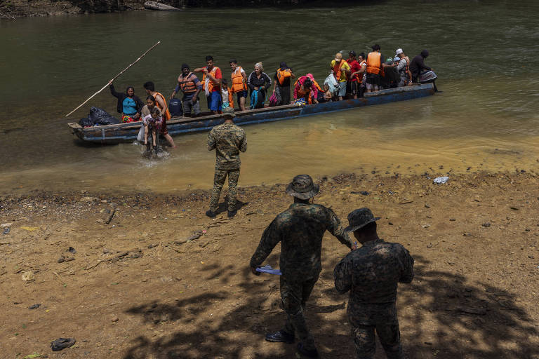Migrantes desembarcam de canoa ao chegar na Estação de Recepção Migratória de Lajas Blancas, no Panamá, após viagem de cerca de 5 horas por rio