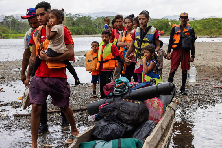 Famílias de migrantes venezuelanos se preparam para embarcar em pirágua (canoa) na comunidade indígena de Bajo Chiquito que os levaria pelo rio Tuqueza até a Estação de Recepção Migratória de Lajas Blancas, no Panamá; elas haviam acabado de cruzar a selva de Darién