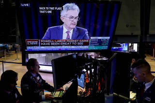 FILE PHOTO: Traders work as a screen shows Federal Reserve Chairman Jerome Powell's news conference after the U.S. Federal Reserve interest rates announcement on the floor of the  NYSE in New York