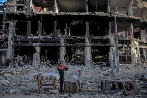 TOPSHOT - A Palestinian vendor waits for customers in front of a building destroyed by Israeli bombardment in Gaza City on March 3, 2024, amid the ongoing conflict between Israel and the Hamas movement. (Photo by AFP)
