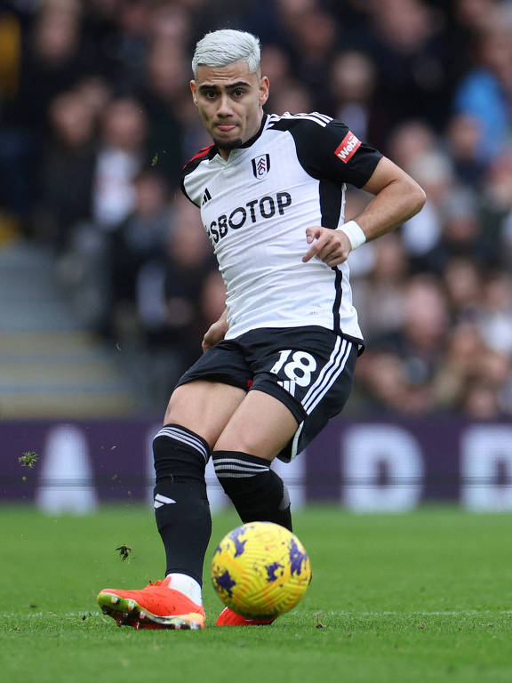 Andreas Pereira passa a bola com o pé direito em jogo do Fulham contra o Aston Villa, em Londres, pelo Campeonato Inglês; no seu calção aparece o número 18