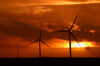 The sun sets behind power-generating windmill turbines near Waremme