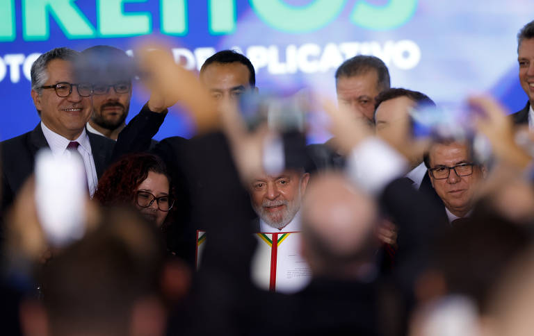 Presidente Lula cercado de celulares em evento no Palácio do Planalto.