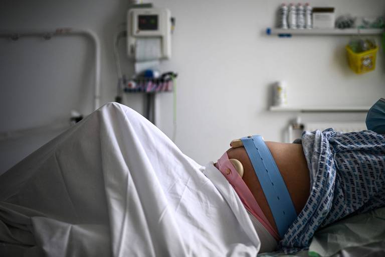 Mulher grávida deitada em uma maca de um hospital