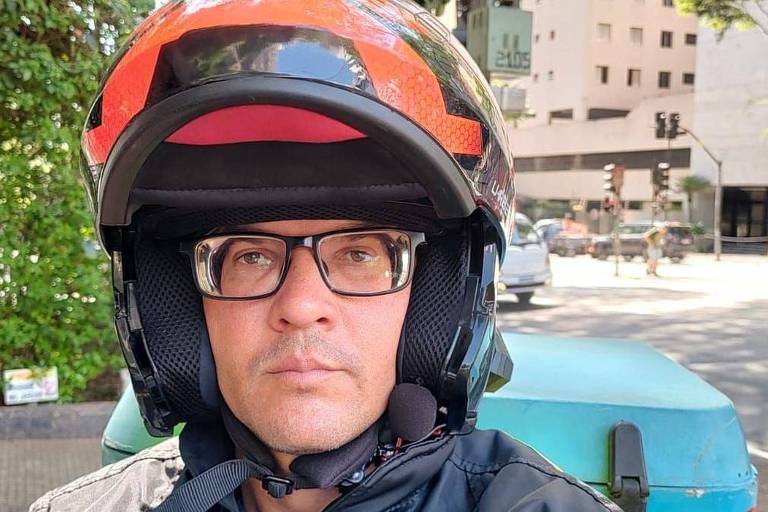 De capacete, Rodrigo Silva tira selfie durante trabalho como entregador em São Paulo

