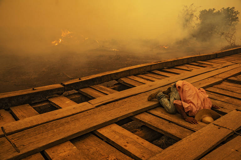 Voluntário procura foco de incêndio sob ponte de madeira da Transpantaneira, no Pantanal do Mato Grosso
