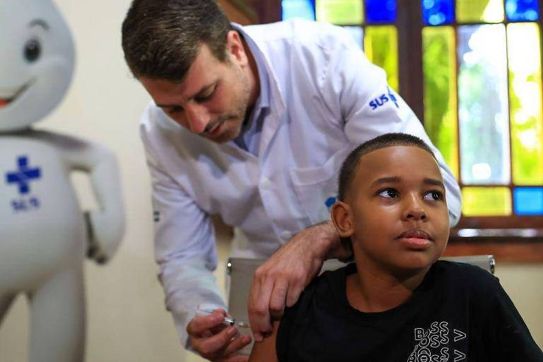 Menino negro recebe a vacina contra a dengue 