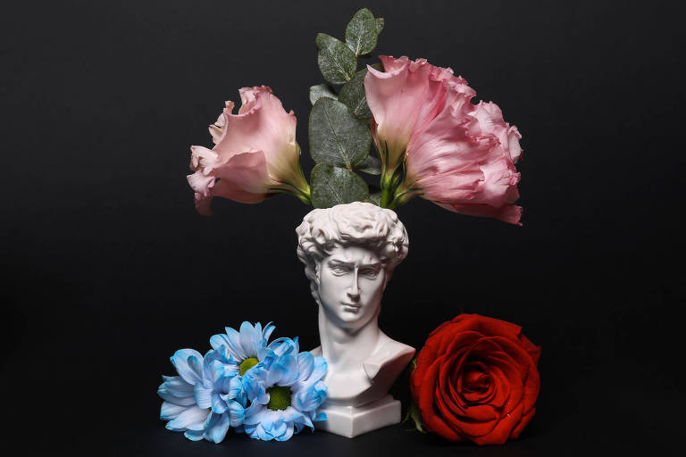 Fotografia da escultura de um busto masculino com flores ao redor