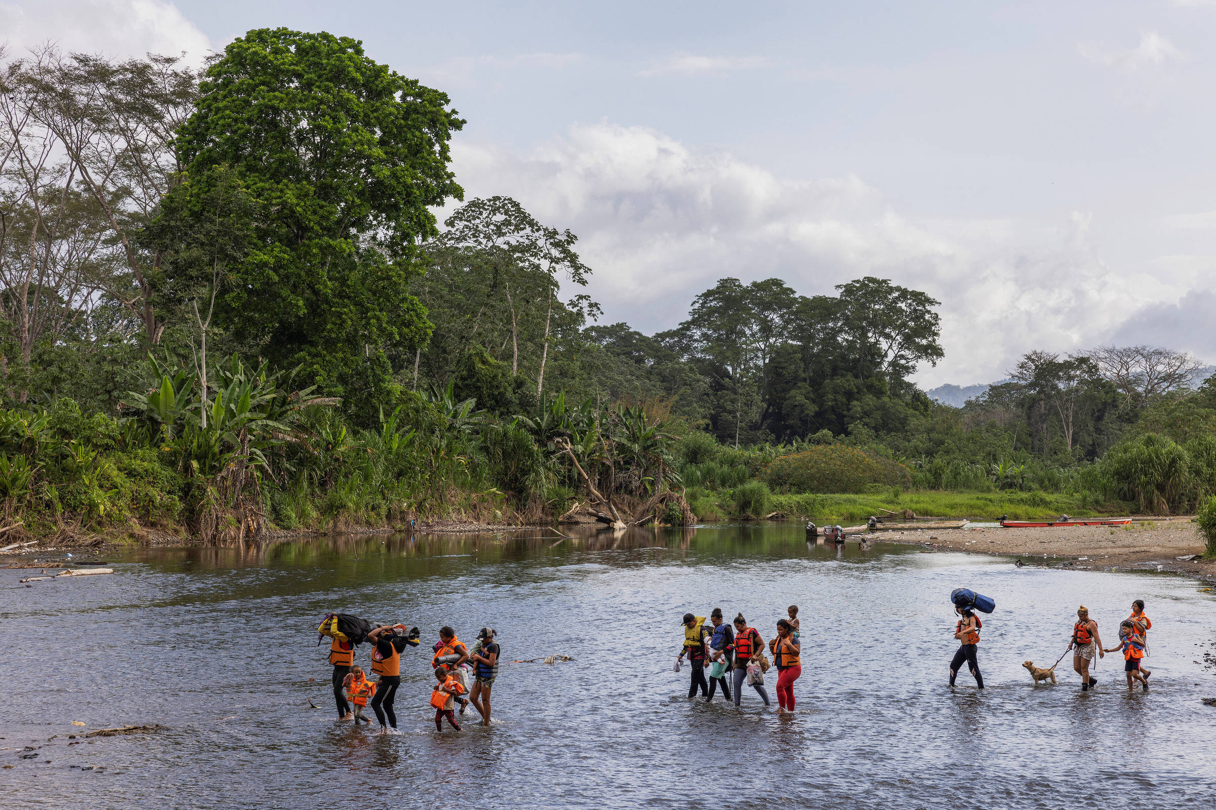 Migrantes atravessam o rio Tuqueza para chegar à área de embarque das canoas, ou piráguas, e seguir viagem