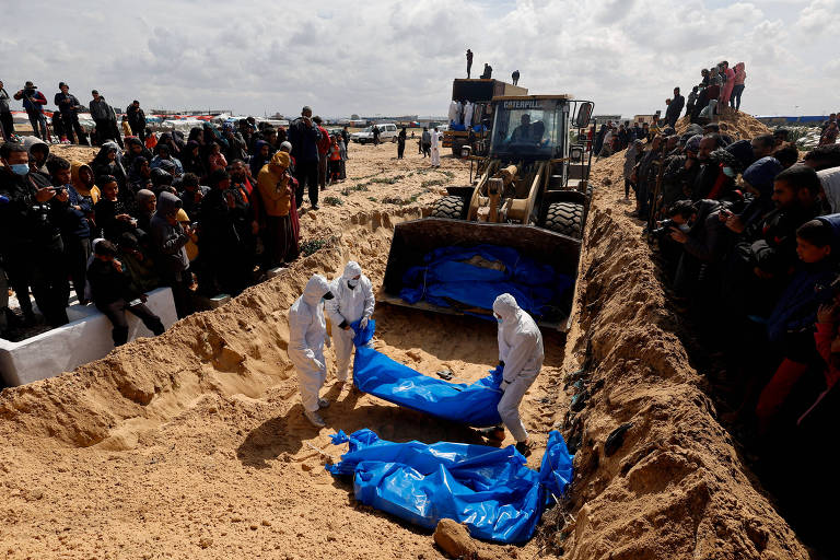 Corpos de palestinos são enterrados em valas comuns em Rafah, no sul da Faixa de Gaza