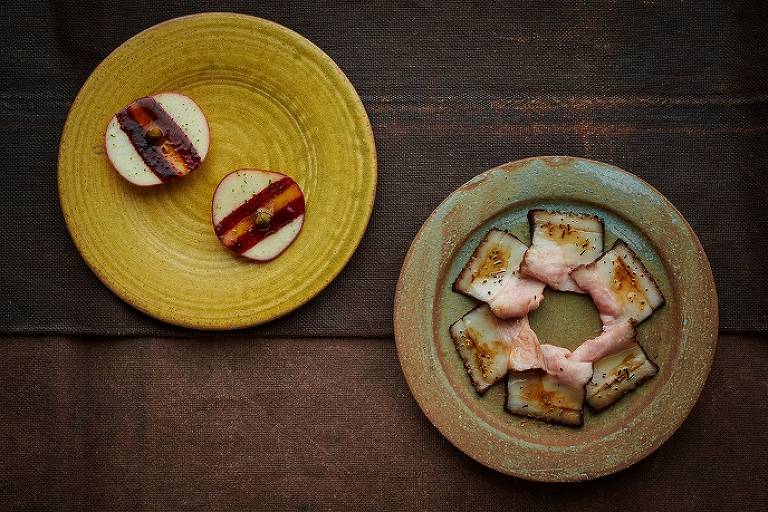 Pratos do chef René Redzepi (à esquerda, maçã com groselha e erva, e, ao lado, barriga de javali grelhada)