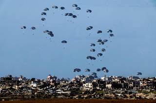 Packages dropped from a military aircraft fall towards northern Gaza, as seen from Israel