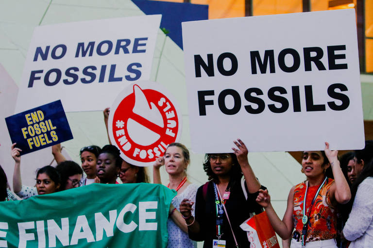 Ativistas climáticas protestam segurando diversas placas contra combustíveis fósseis 