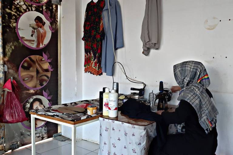 Bahara é uma mulher muçulmana que usa véu, ela está de costas sentada em uma máquina de costura