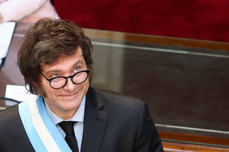 Usando óculos e a faixa presidencial, o presidente da Argentina, Javier Milei, sorri ao olhar para o alto em visita ao Congresso do país