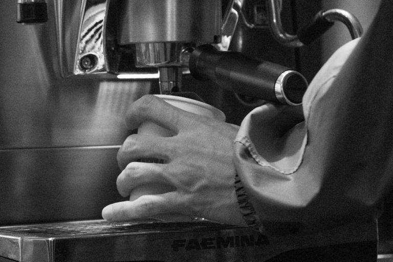 Mão segura um copo em uma máquina de café