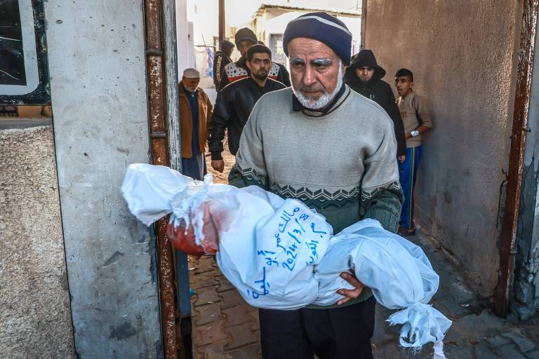 Palestino leva corpo de criança ao hospital Al-Najar, em Rafah, no sul da Faixa de Gaza; cidade superlotada tem sido bombardeada desde início do conflito, e Israel ameaça invadir por terra