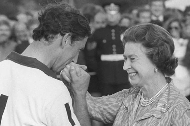 Rei Charles aparece jovem, de perfil, dando um beijo na mão de sua mãe, a Rainha Elizabeth