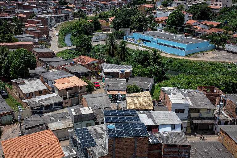 vista aérea foto de painel solar em imóvel com tijolo aparente ao lado de casas em bairro da periferia de salvador