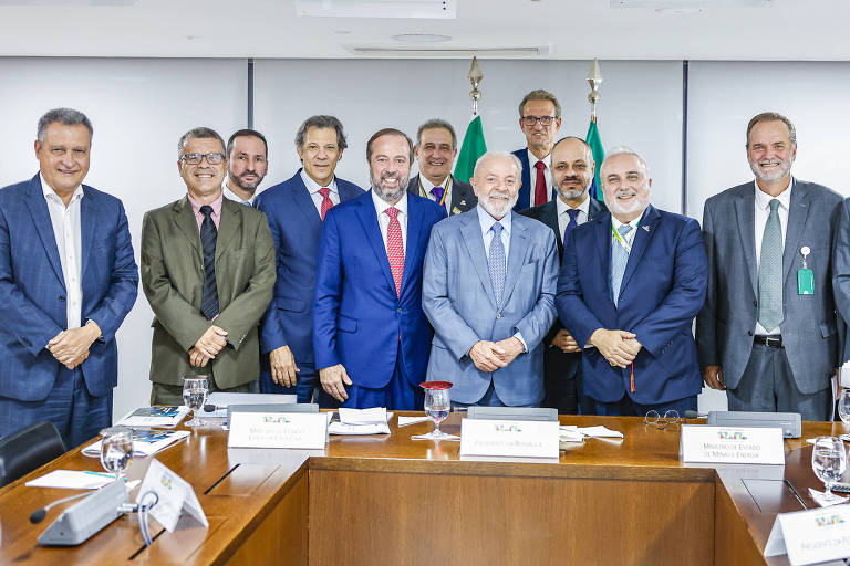 12 homens de terno posam em sala de reunião atrás de mesa em formato retangular. Lula está no centro