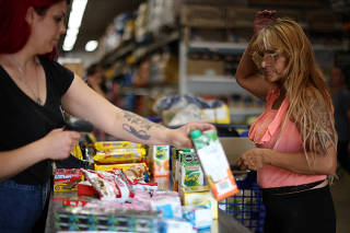 A woman gestures before paying at a supermarket checkout counter, in Buenos Aires