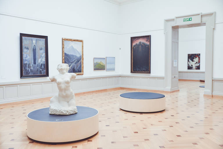 Sala do Museu de Arte e História, em Genebra, com um busto no meio e quadros nas paredes