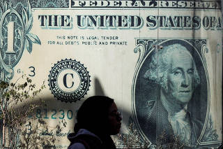 A woman walks past a currency exchange point, displaying an image of the U.S. dollar, in Cairo