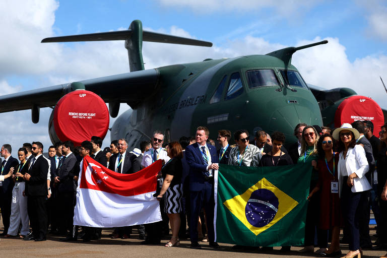 Delegação brasileira posa para fotos ao lado de uma aeronave Embraer C-390 Millennium durante o Singapore Airshow no Centro de Exposições Changi