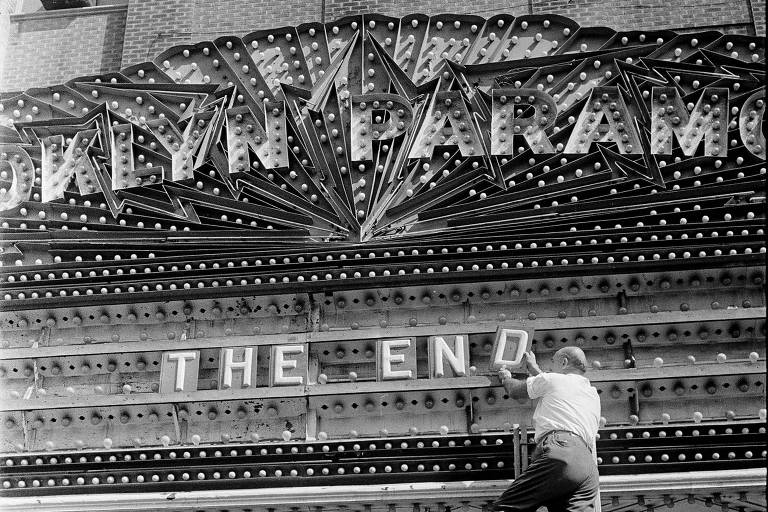 Homem mexe no letreiro da marquise do cinema Brooklyn Paramount Theatre, em Nova York, em agosto de 1962