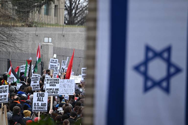 pessoas com bandeiras palestinas protestam ao lado de bandeira israelense pendurada