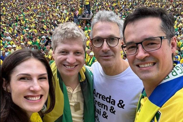 Os quatro sorriem em selfie e estão em caminhão de som acima de multidão que veste verde e amarelo